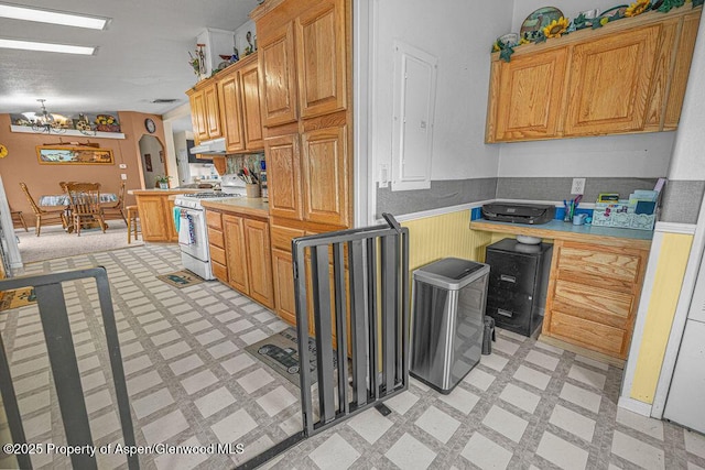 1097 Kowach Dr, Craig, CO 81625 - kitchen featuring white gas range oven, light floors, under cabinet range hood, a wainscoted wall, and a chandelier