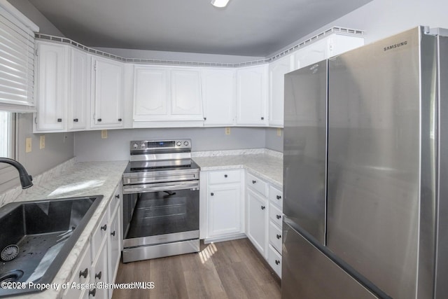 750 Breeze St, Craig, CO 81625 - kitchen featuring appliances with stainless steel finishes, dark wood-type flooring, white cabinetry, and light stone countertops