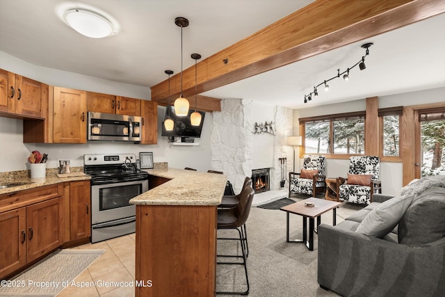 kitchen with stainless steel appliances, a kitchen breakfast bar, kitchen peninsula, decorative light fixtures, and a fireplace