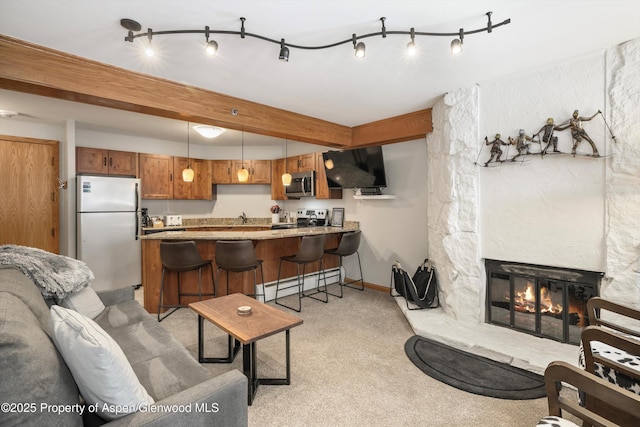 living room with beam ceiling, sink, a baseboard radiator, a stone fireplace, and light colored carpet