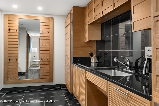 kitchen featuring tasteful backsplash, sink, and dark tile patterned flooring