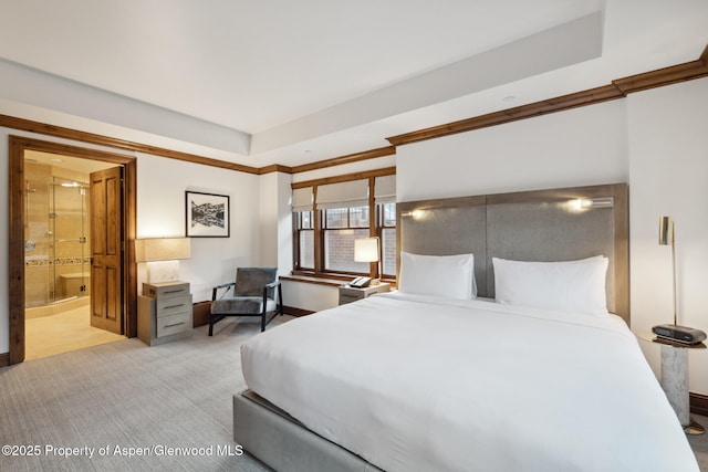 bedroom with light carpet, ensuite bath, a tray ceiling, and ornamental molding