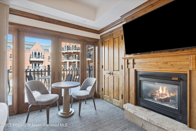 sitting room with ornamental molding, a glass covered fireplace, and carpet flooring