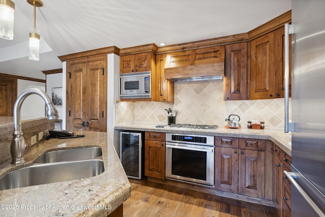 kitchen featuring wall chimney exhaust hood, appliances with stainless steel finishes, a sink, beverage cooler, and hardwood / wood-style floors