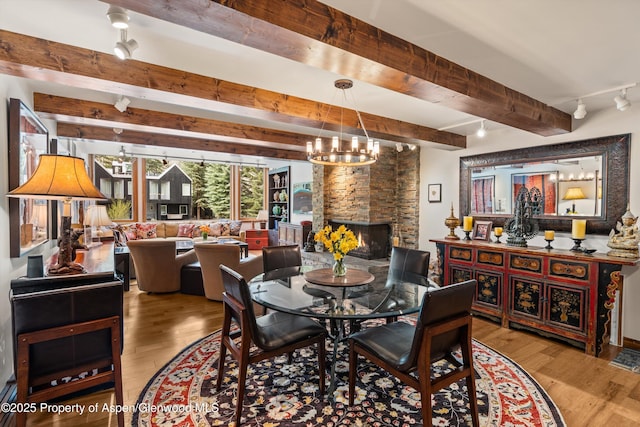 926 Waters Ave # 203, Aspen, CO 81611 - dining room with beam ceiling, wood finished floors, a chandelier, and a stone fireplace
