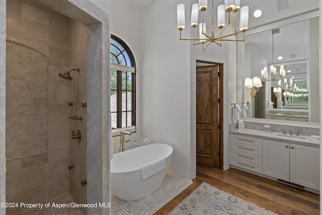 bathroom featuring plus walk in shower, hardwood / wood-style floors, vanity, and a chandelier