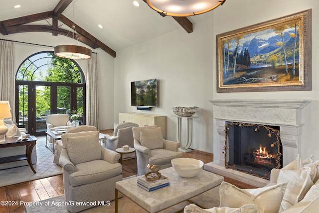 living room with hardwood / wood-style flooring, vaulted ceiling with beams, and a fireplace