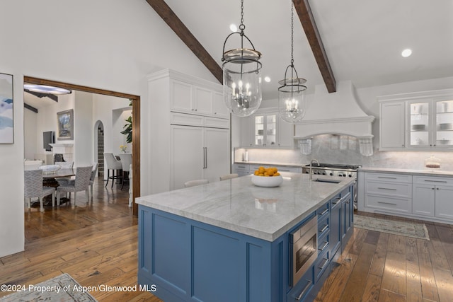 kitchen with blue cabinetry, white cabinetry, backsplash, built in appliances, and custom range hood