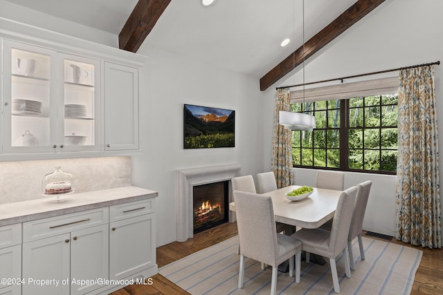 dining room with beam ceiling and wood-type flooring