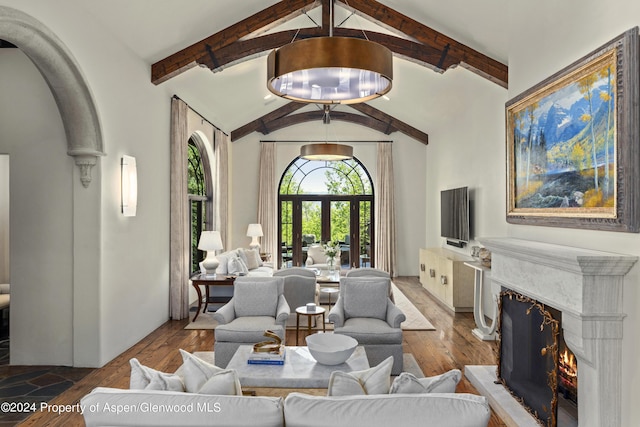 living room with lofted ceiling with beams, light wood-type flooring, and a high end fireplace