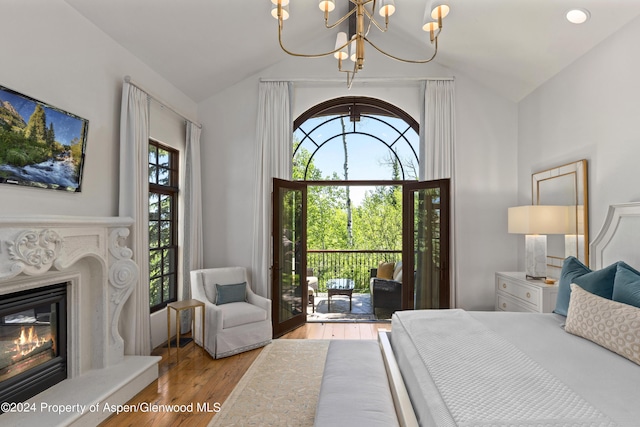 bedroom featuring a high end fireplace, a chandelier, lofted ceiling, and light hardwood / wood-style floors