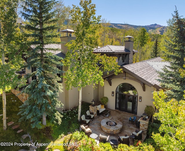 rear view of property with a mountain view, french doors, a fire pit, and a patio area