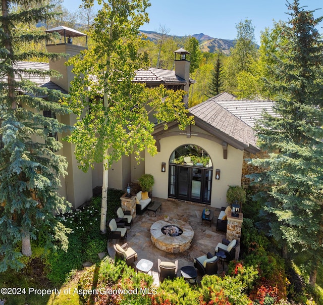 rear view of property featuring a mountain view, french doors, a patio, and an outdoor fire pit