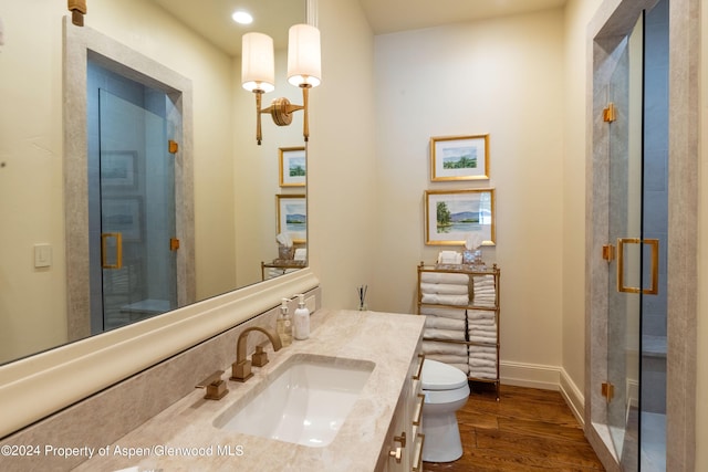 bathroom with wood-type flooring, vanity, toilet, and an enclosed shower