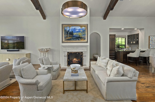 living room with hardwood / wood-style flooring, beam ceiling, and a high end fireplace