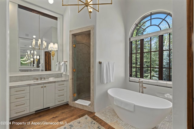 bathroom with vanity, hardwood / wood-style floors, plus walk in shower, and an inviting chandelier