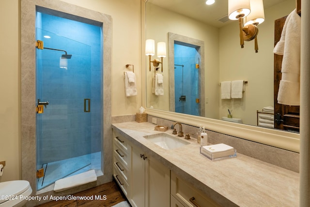 bathroom with walk in shower, hardwood / wood-style flooring, vanity, and toilet