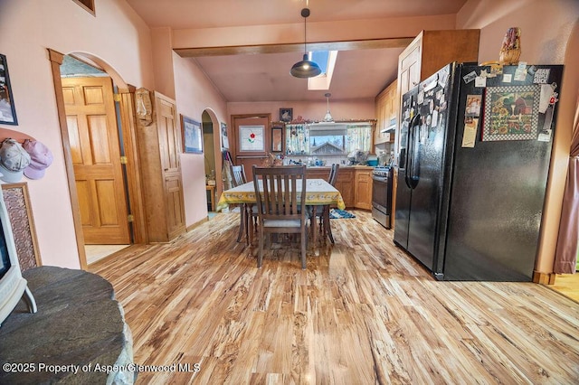 dining room featuring arched walkways and light wood finished floors