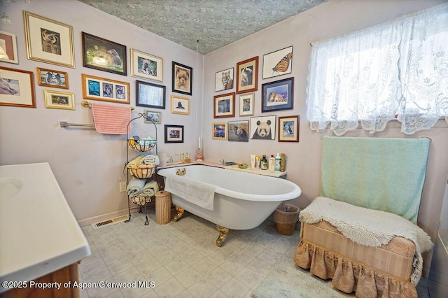 bathroom featuring visible vents, baseboards, a freestanding bath, and vanity