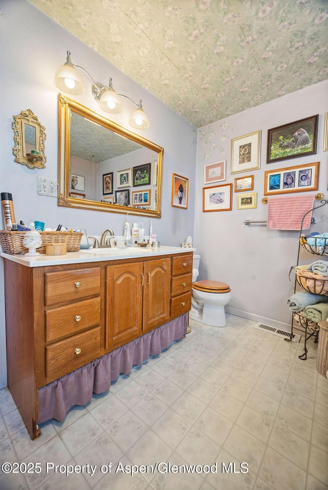 bathroom featuring visible vents, vanity, toilet, and baseboards