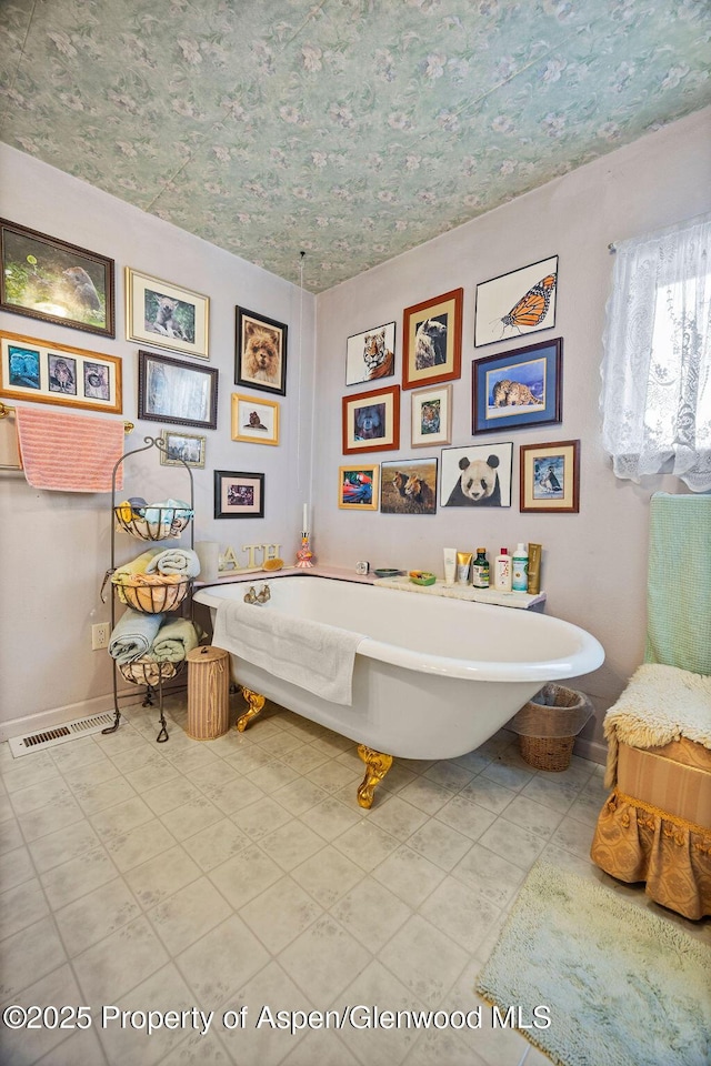 full bath featuring tile patterned flooring, a freestanding tub, and baseboards