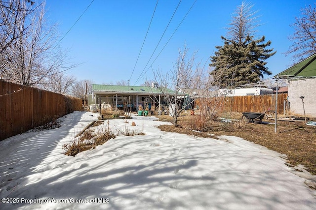 snow covered property featuring covered porch, fence, and metal roof