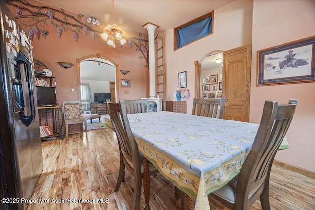 dining space with arched walkways, light wood-type flooring, and decorative columns