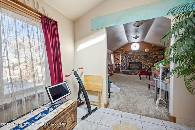 office area with lofted ceiling, tile patterned floors, carpet floors, and a stone fireplace