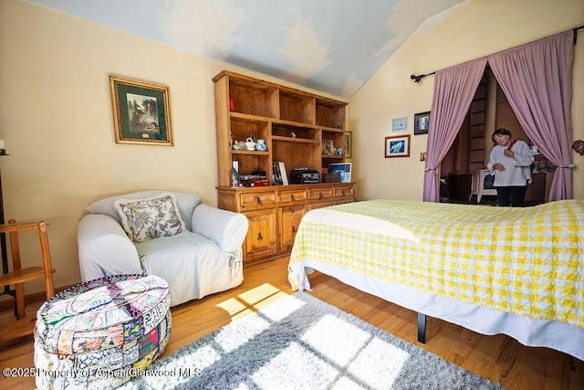 bedroom with vaulted ceiling and light wood-style flooring