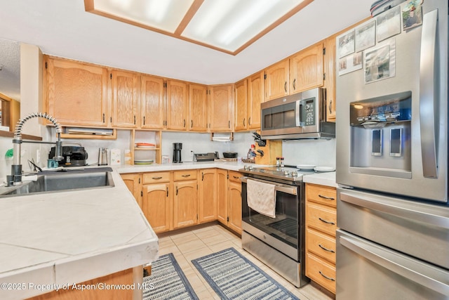 565 Sandrock Dr, Craig, CO 81625 - kitchen with stainless steel appliances, a sink, light countertops, light tile patterned floors, and light brown cabinetry