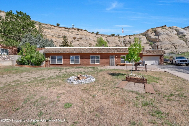 565 Sandrock Dr, Craig, CO 81625 - view of front facade with concrete driveway, a fire pit, a garage, and a front yard