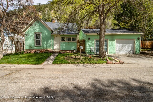 824 Lincoln Ave, Glenwood Springs, CO 81601 - view of front of house featuring an attached garage, a chimney, concrete driveway, and fence
