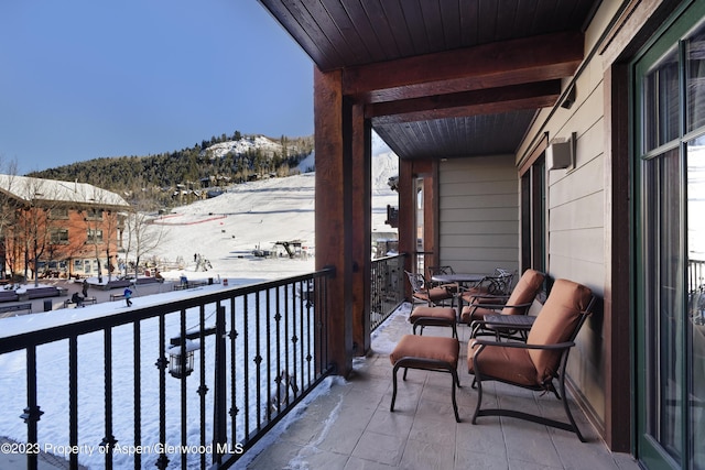 snow covered back of property featuring a mountain view