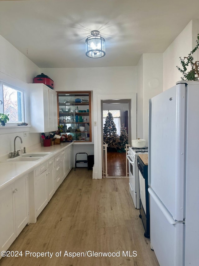 kitchen with white cabinetry, sink, light hardwood / wood-style floors, and white appliances