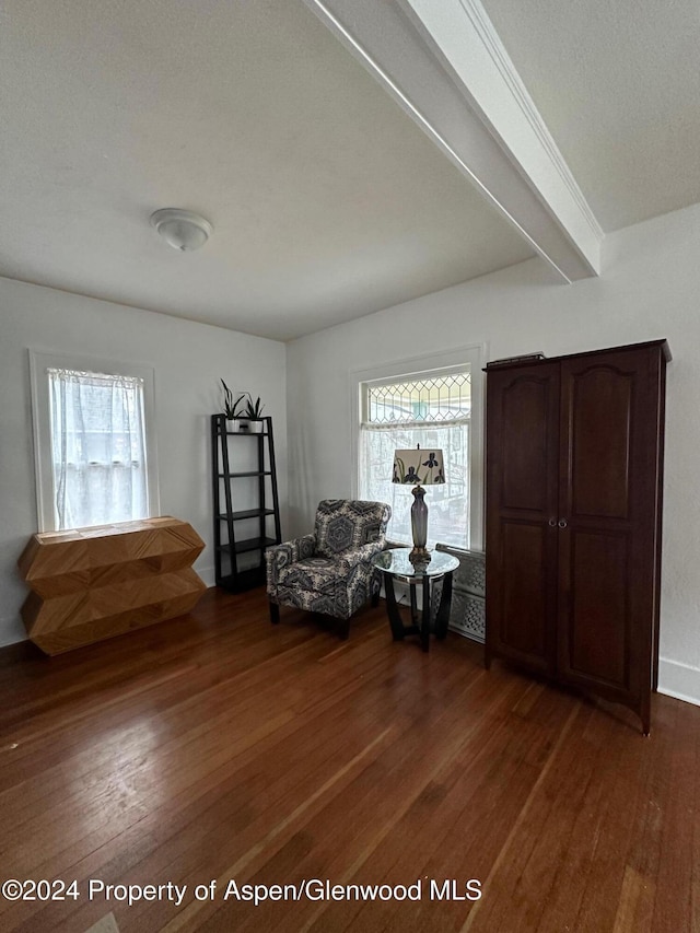 living area with beamed ceiling and dark hardwood / wood-style floors