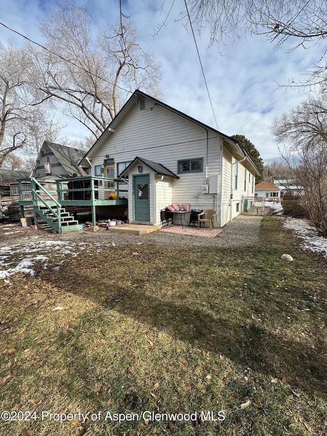 back of property with a yard, a patio, and a wooden deck