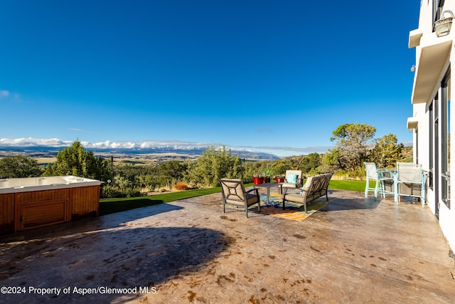 view of yard with a mountain view, a patio area, and a hot tub