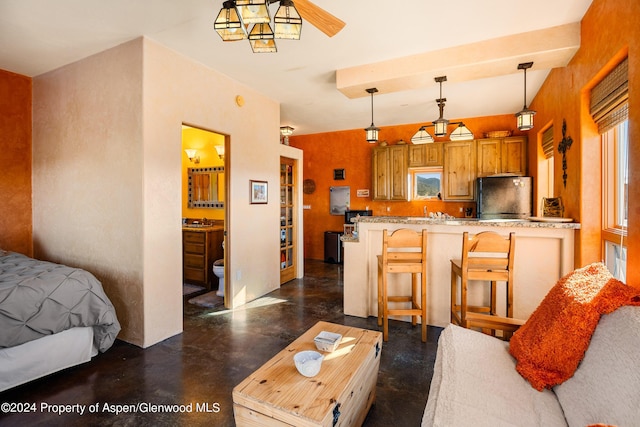 kitchen featuring fridge, decorative light fixtures, a healthy amount of sunlight, a kitchen bar, and kitchen peninsula