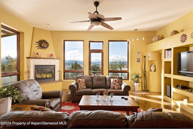 living room featuring ceiling fan and a tiled fireplace