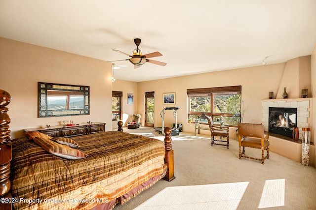 bedroom featuring ceiling fan, light colored carpet, and a tile fireplace