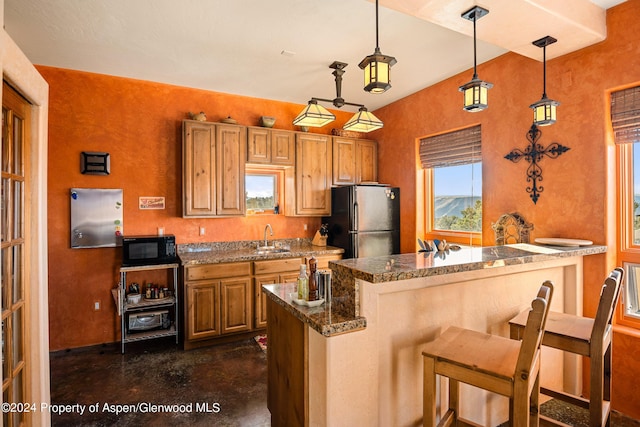 kitchen with kitchen peninsula, stainless steel refrigerator, a breakfast bar, and pendant lighting