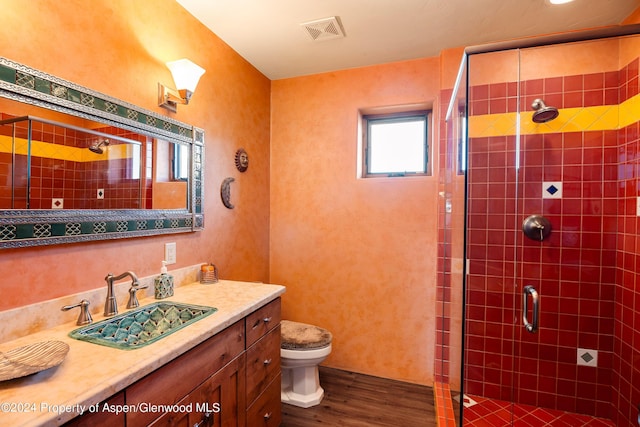 bathroom with wood-type flooring, vanity, toilet, and a shower with door