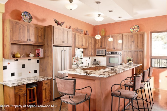 kitchen featuring backsplash, stainless steel appliances, decorative light fixtures, and a kitchen breakfast bar