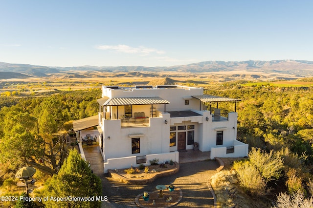 rear view of house featuring a mountain view, a balcony, and a patio