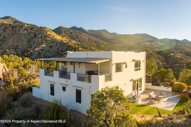 exterior space featuring a mountain view, a patio, a balcony, and a lawn