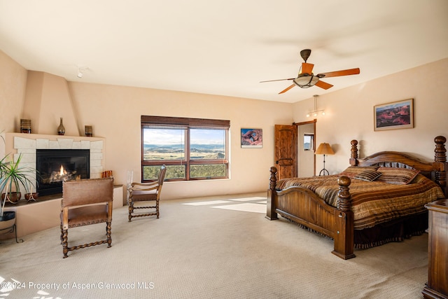 carpeted bedroom featuring ceiling fan and a fireplace