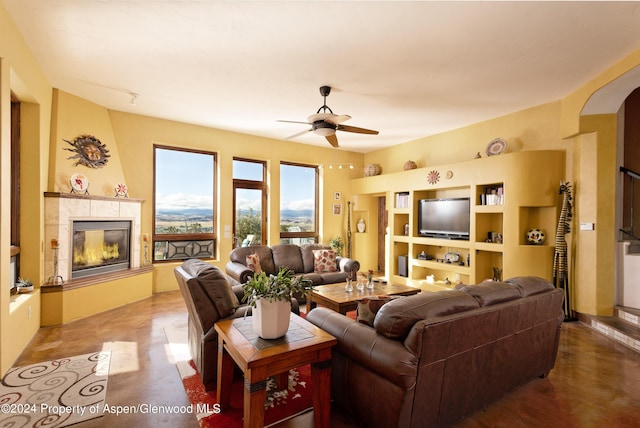 living room with a tile fireplace, ceiling fan, and built in features