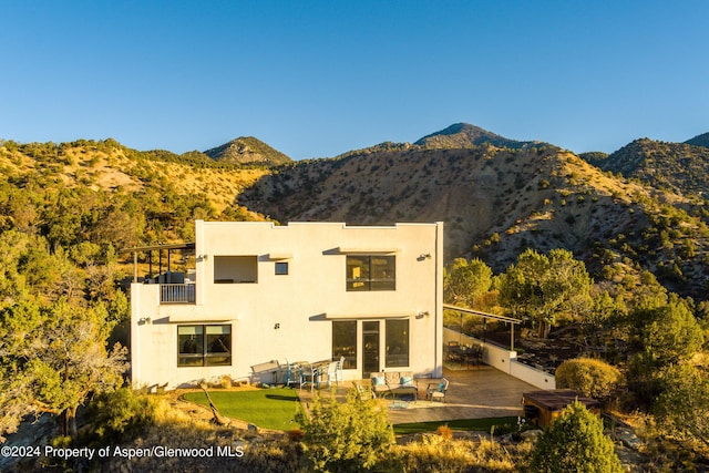 rear view of house featuring a yard, a patio area, a mountain view, and a balcony