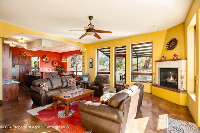 living room with a tile fireplace and ceiling fan