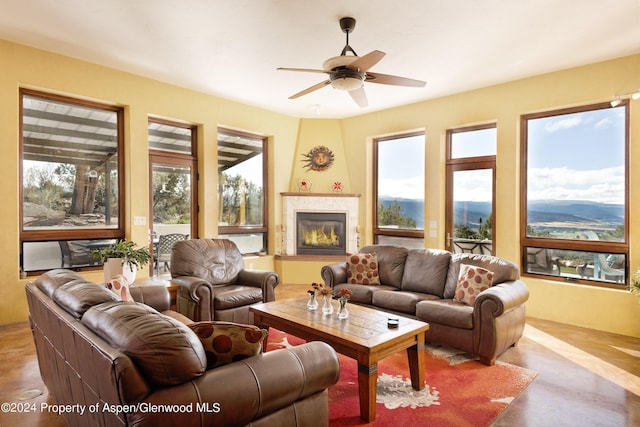 living room with ceiling fan, a mountain view, and a tile fireplace